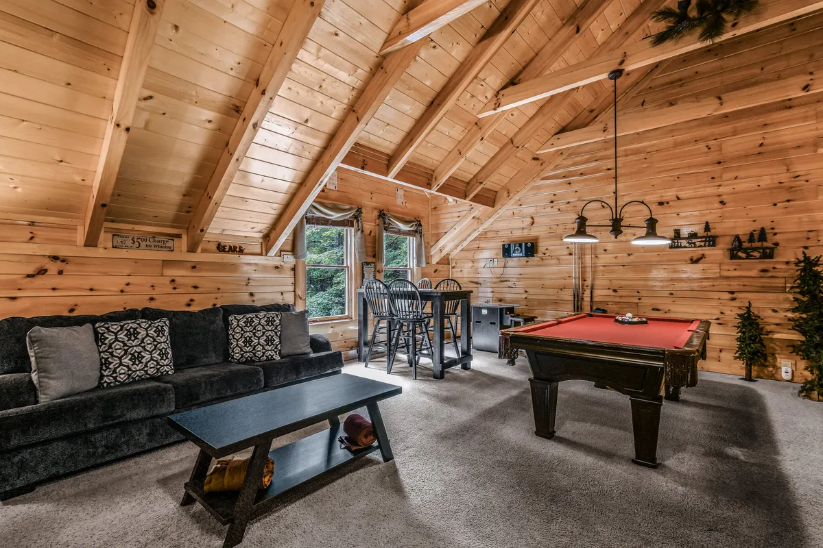 A vibrant interior scene centered on a pool table, with a welcoming seating area, high windows letting in natural light, and a bar table perfect for refreshments during game nights.